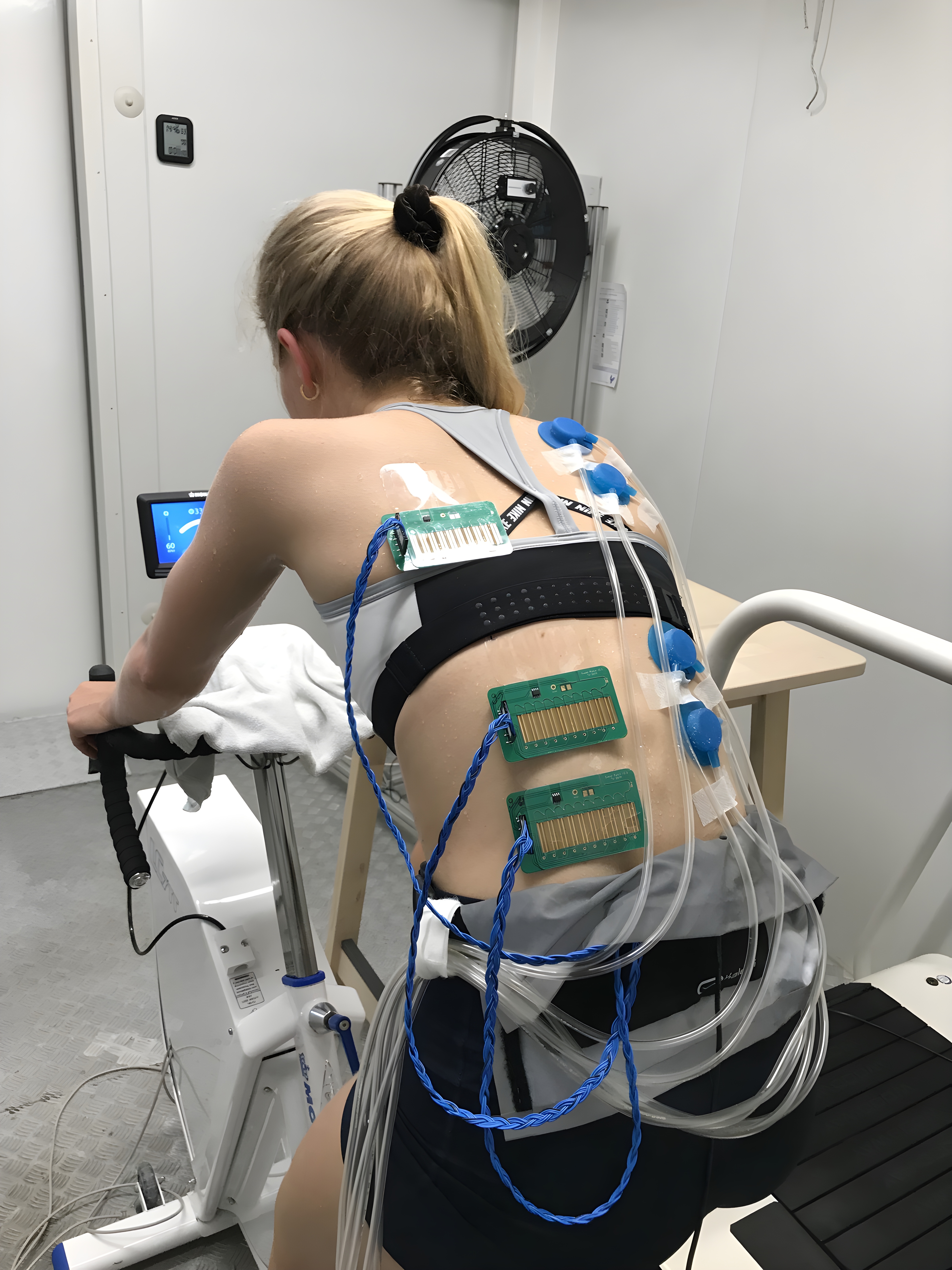 [Translate to English:] Athlete on a home trainer with sensors on her body