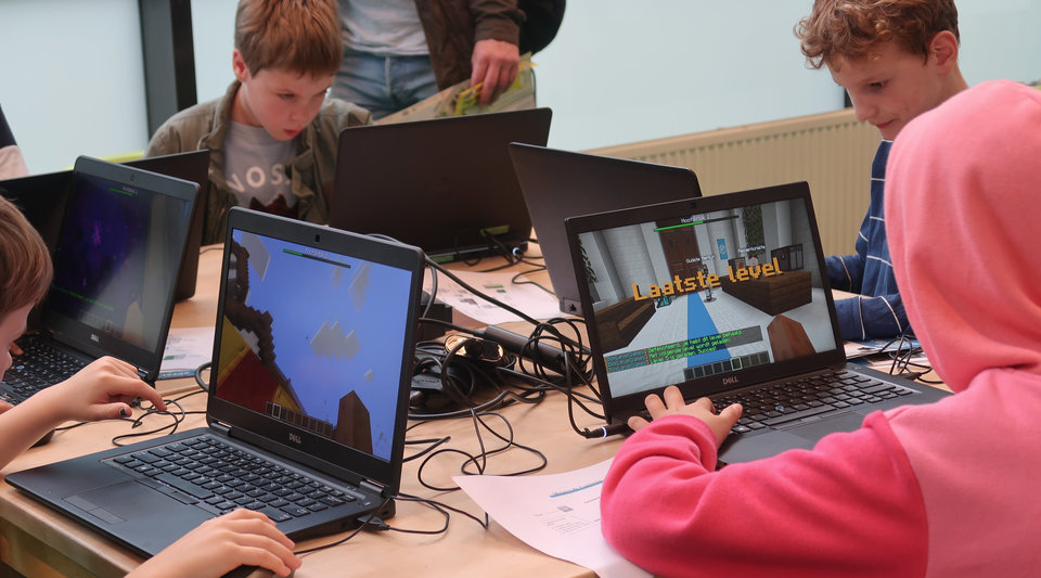 Kinderen leren programmeren in Minecraft tijdens een scholenworkshop.