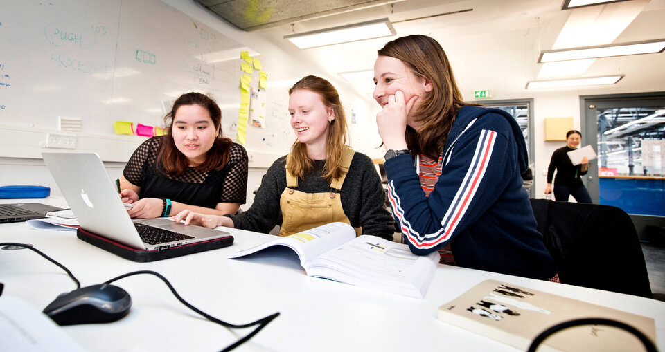 Three smiling students at a desk