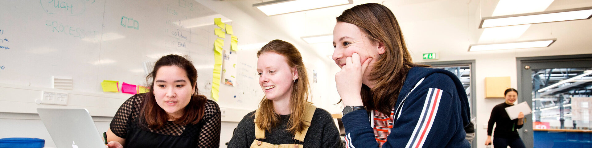 Three students smiling and working at a table