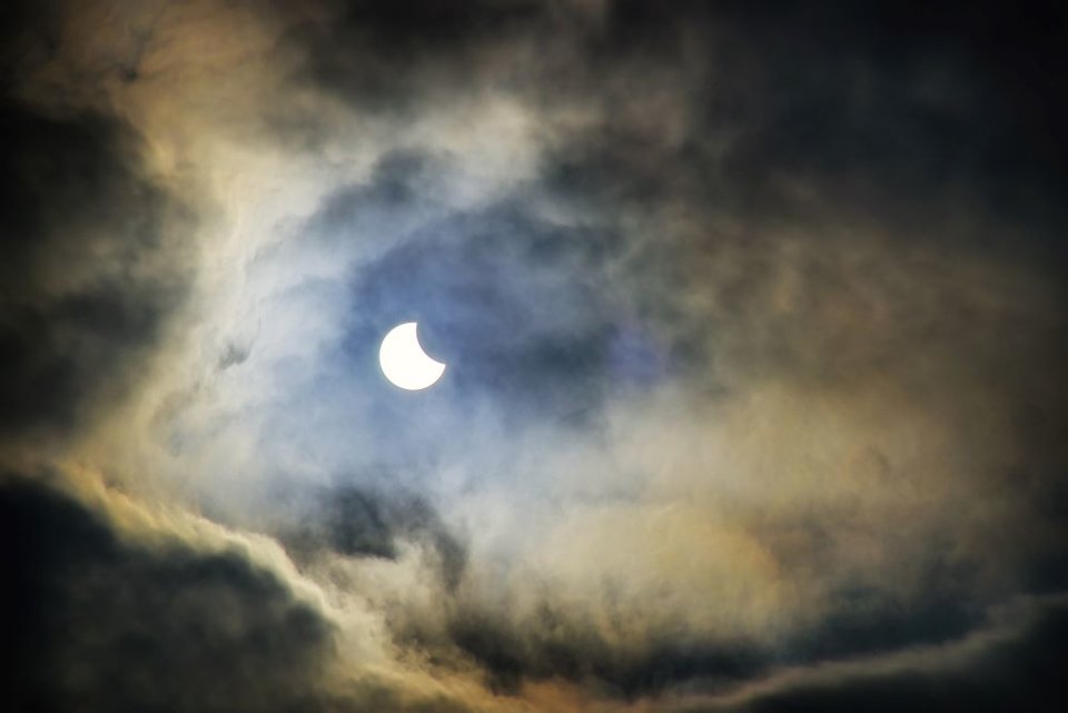 Donkerblauwe lucht met maan in het midden omringd door wolken