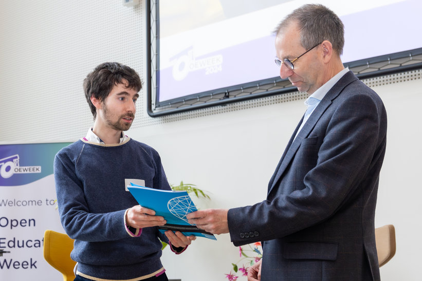 Rob Mudde receives the first booklet of the 11 awarded Open Education Projects by Project Lead Marcell Varkonyi